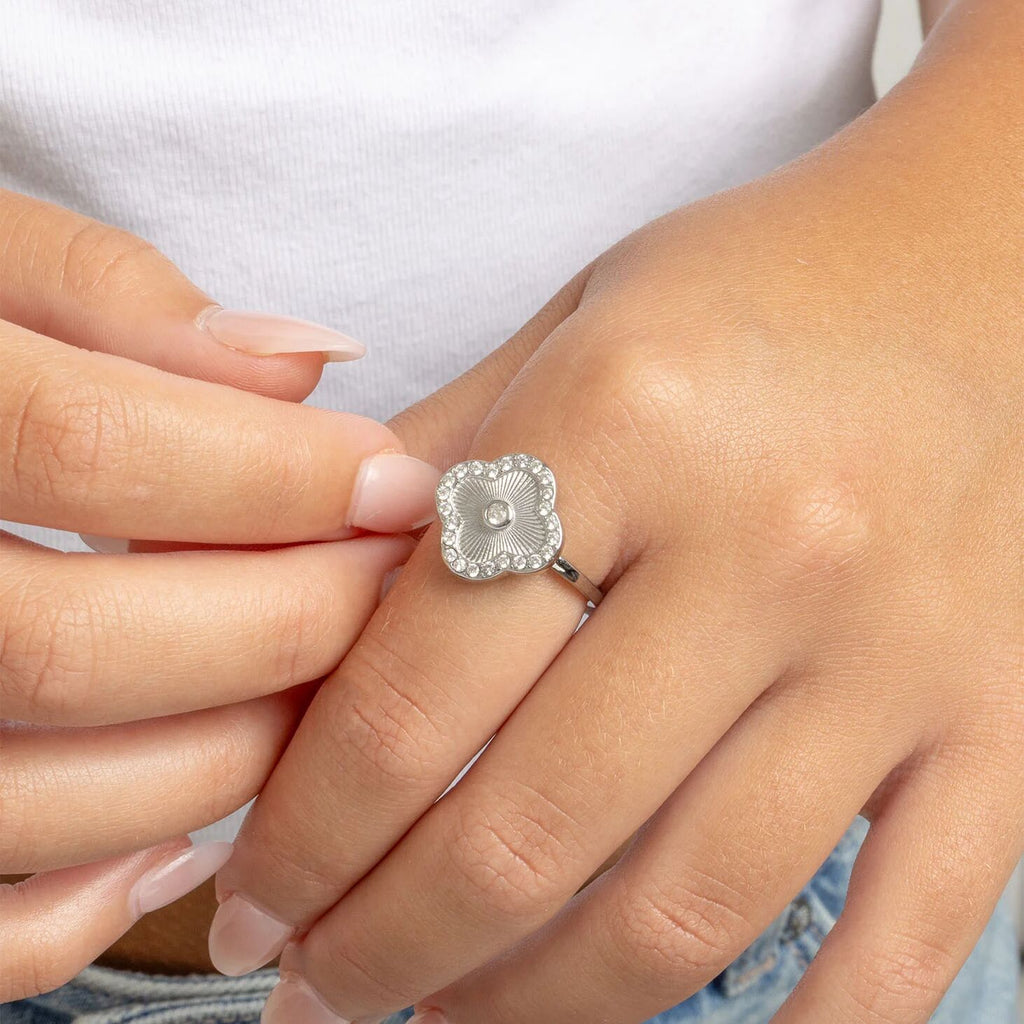 Close-up of a hand wearing a silver Floral Motif Ring with a CZ stones on a white background