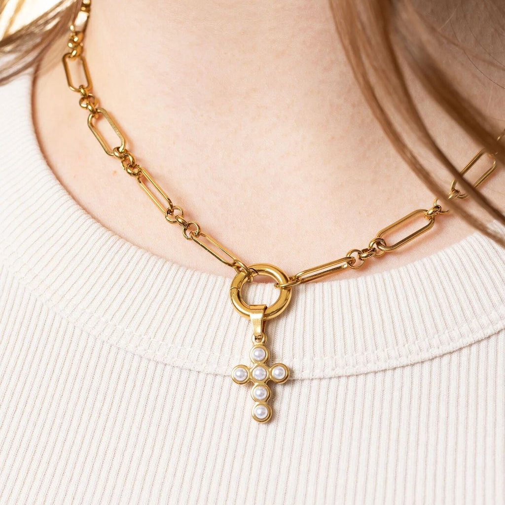 Gold necklace with a cross pendant featuring pearls on a white background