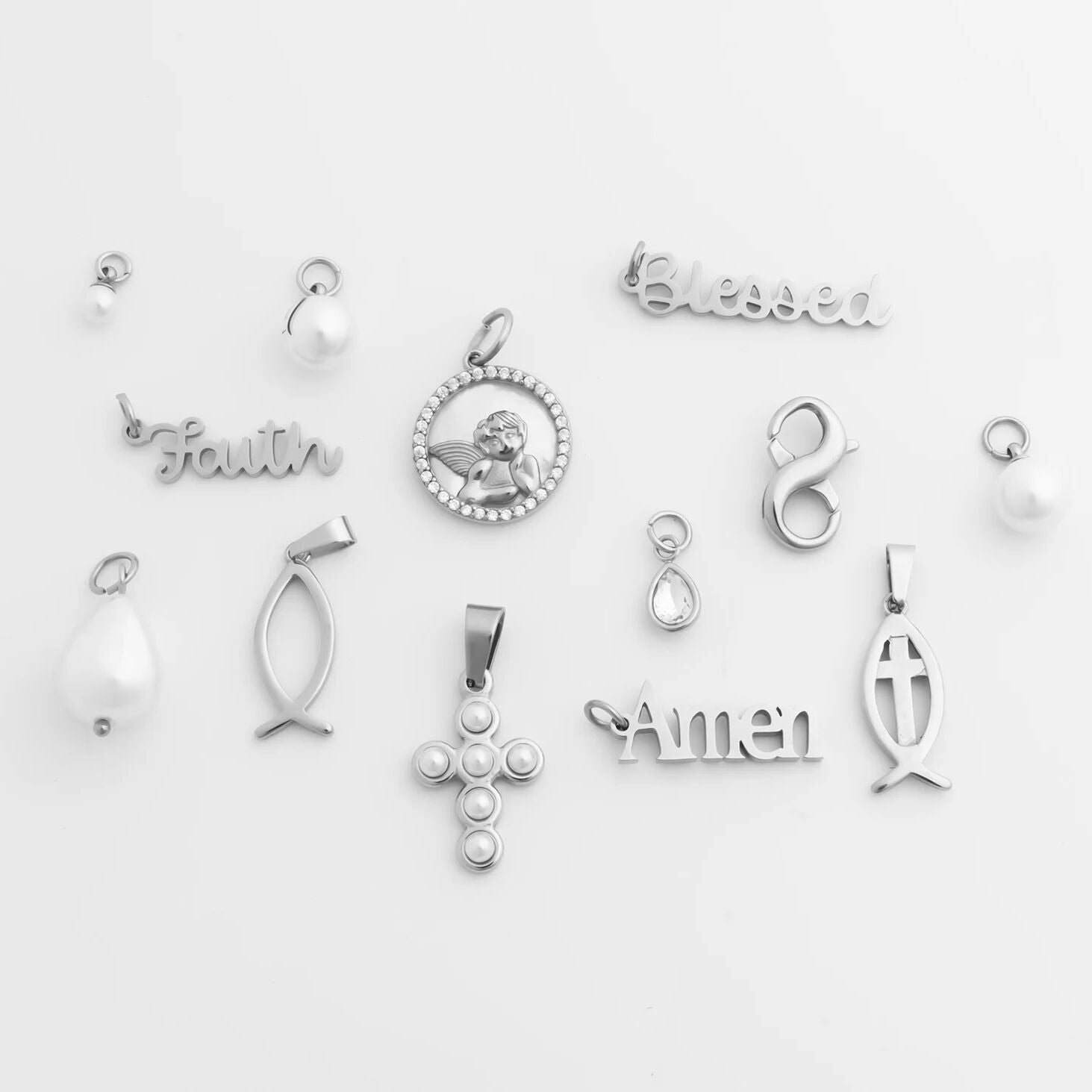 Collection of various silver faith based pendants on a light gray background