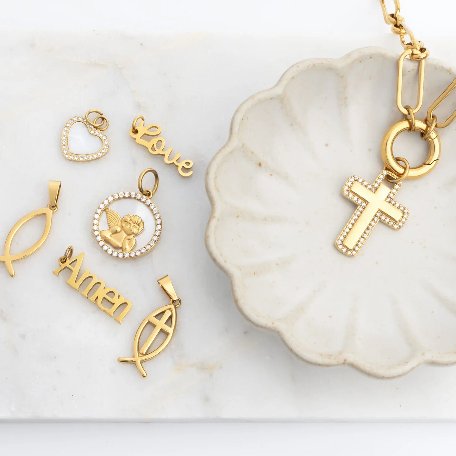 Collection of gold pendants on a white dish with a marble background