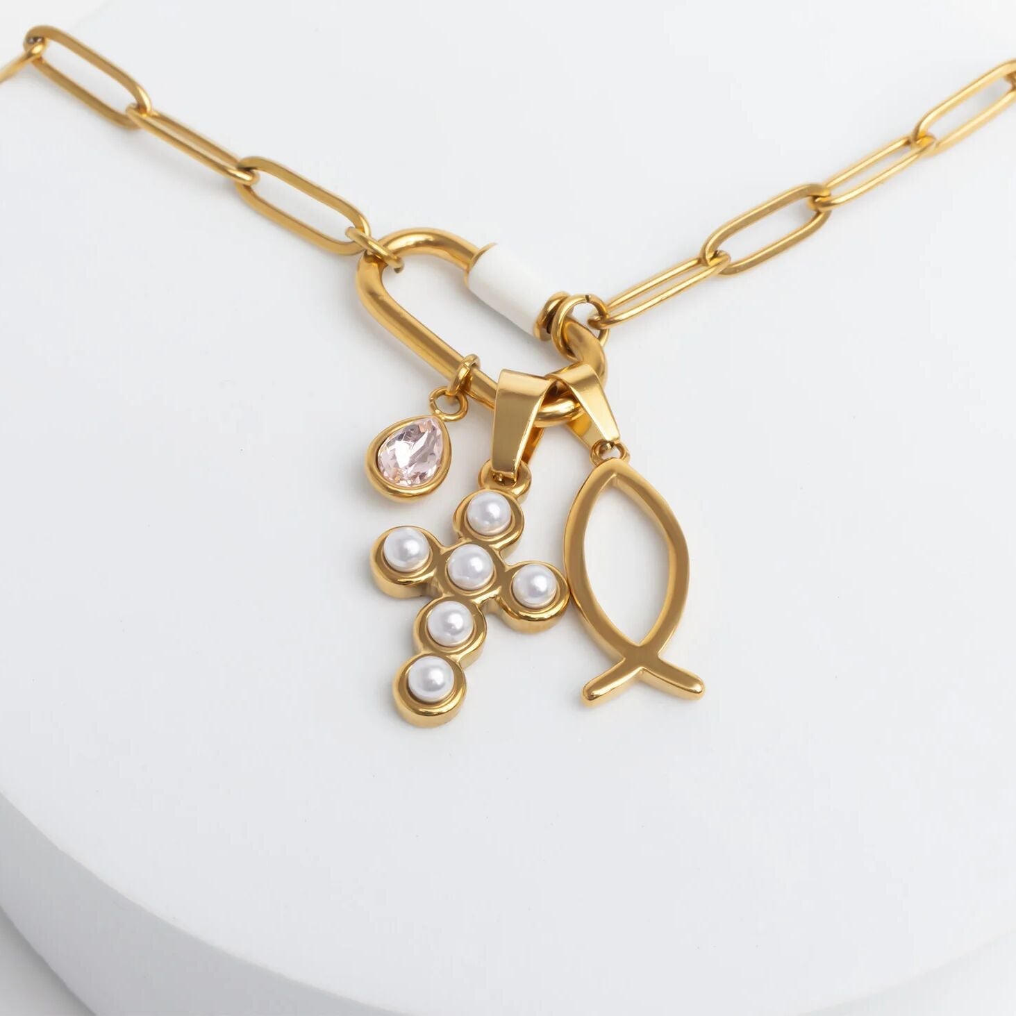 Gold necklace with fish and pearl charm on a white background