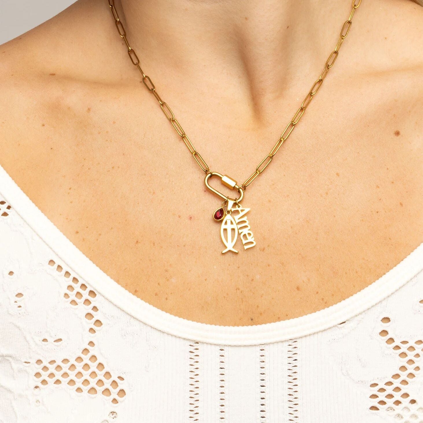 Gold necklace with a pendant on a person wearing a white top.