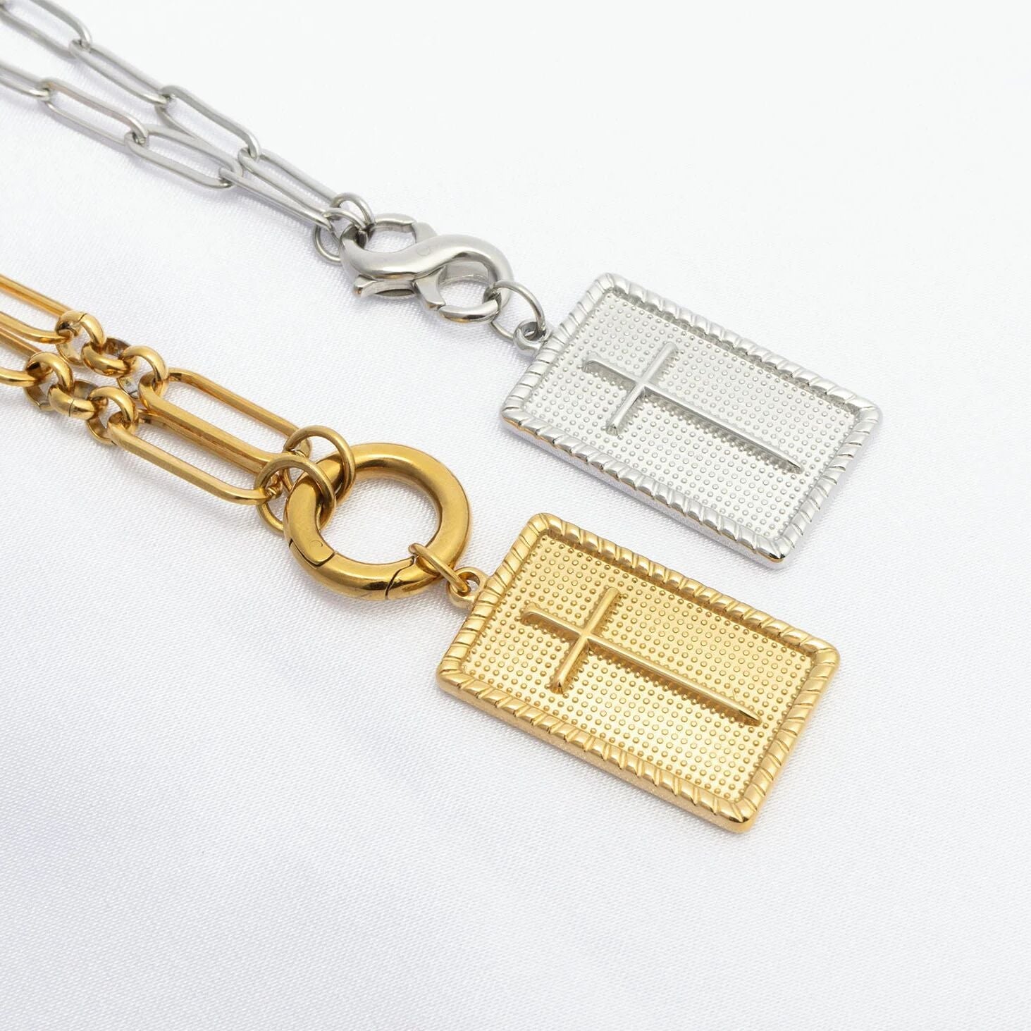 Two gold and silver necklaces with cross pendants on a white background
