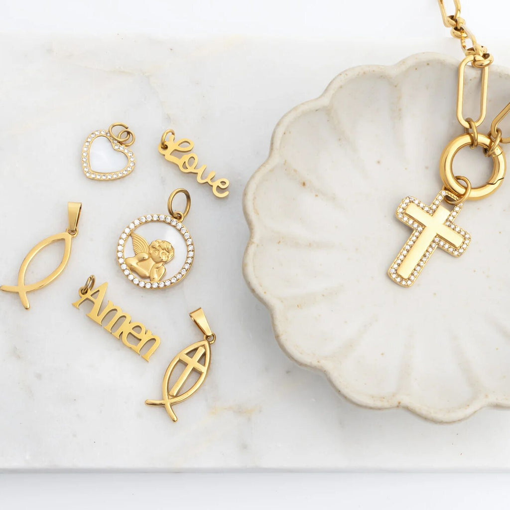 Gold religious pendants on a white dish with a marble background
