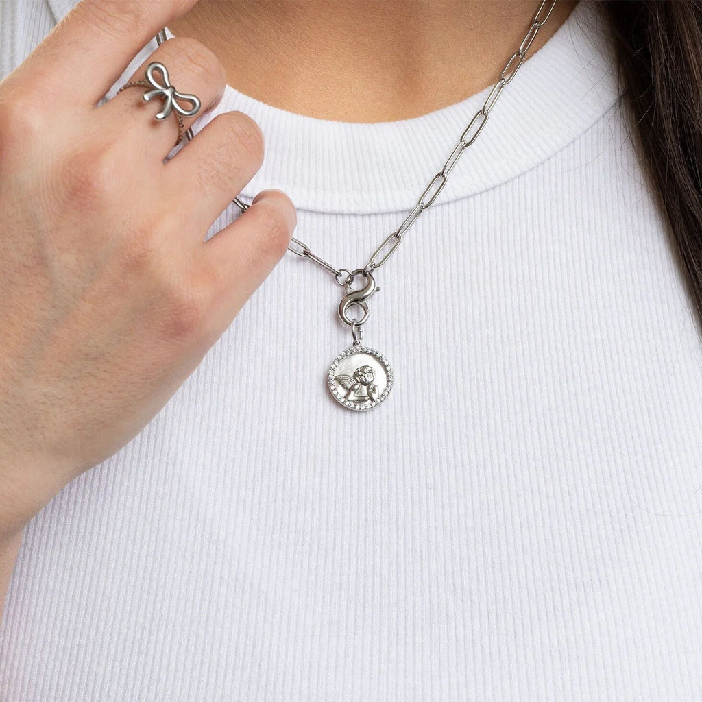 Silver necklace with a pendant held by a hand against a white background