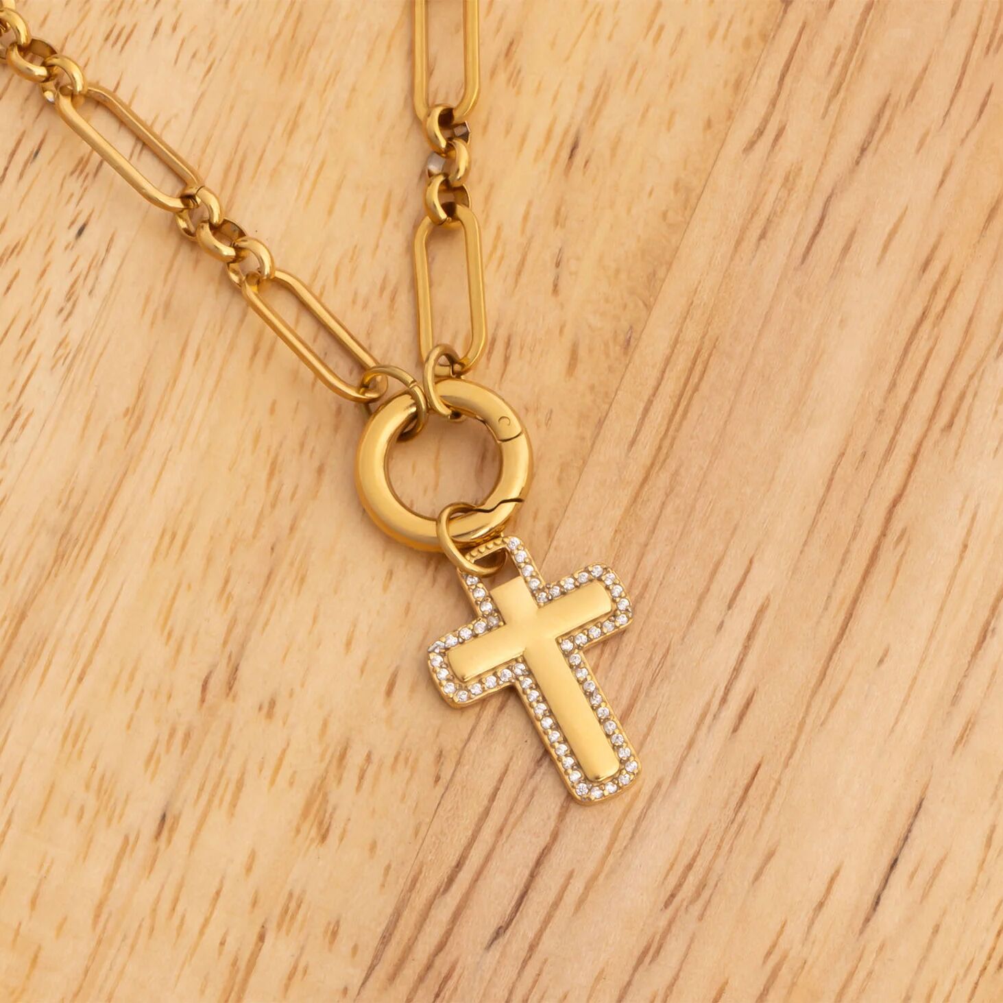 Gold necklace with a cross pendant on a wooden surface