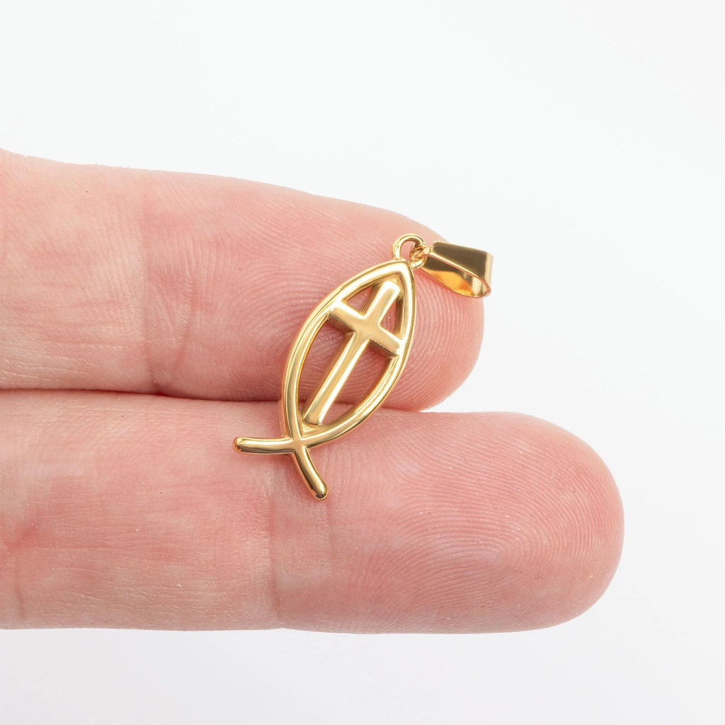 Gold fish pendant held between fingers on a white background