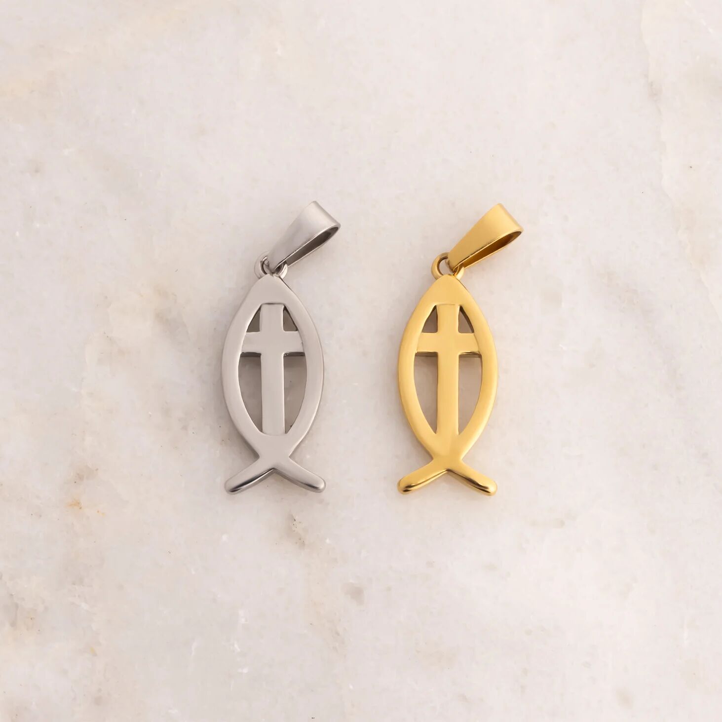 Gold and silver fish-shaped pendants on a marble background