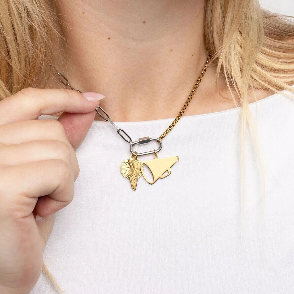 Gold necklace with charms being adjusted by a hand on a white background