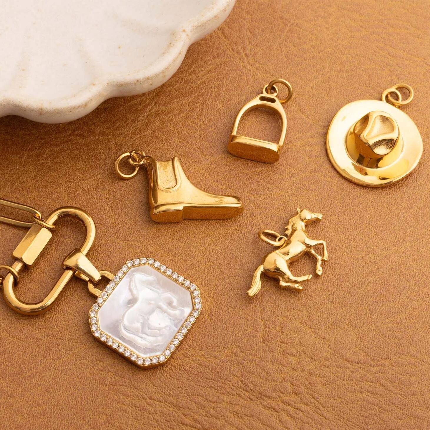 Collection of gold western/ equestrian jewelry charms on a brown surface