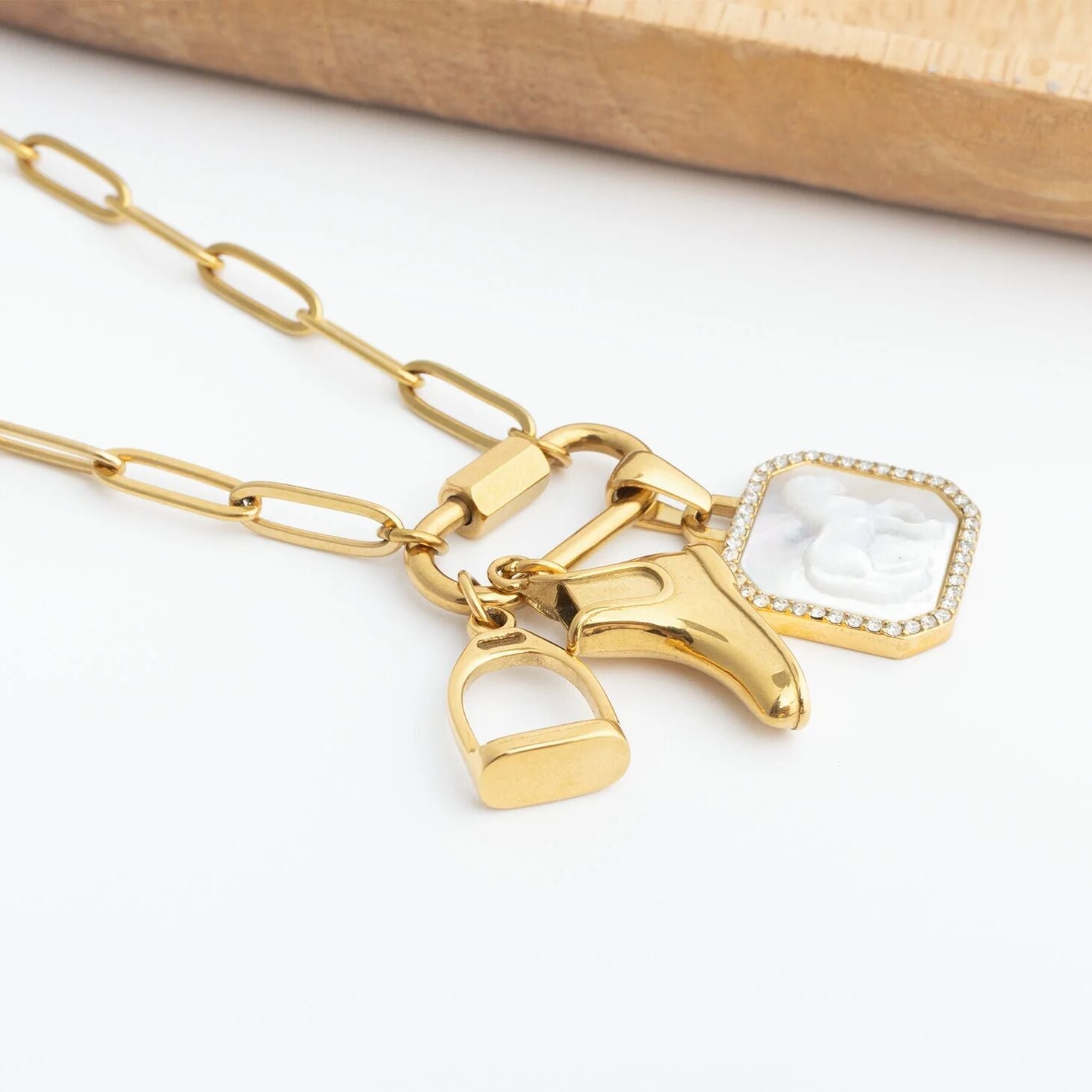 Gold necklace with horse, stirrup and boot charms on a white background