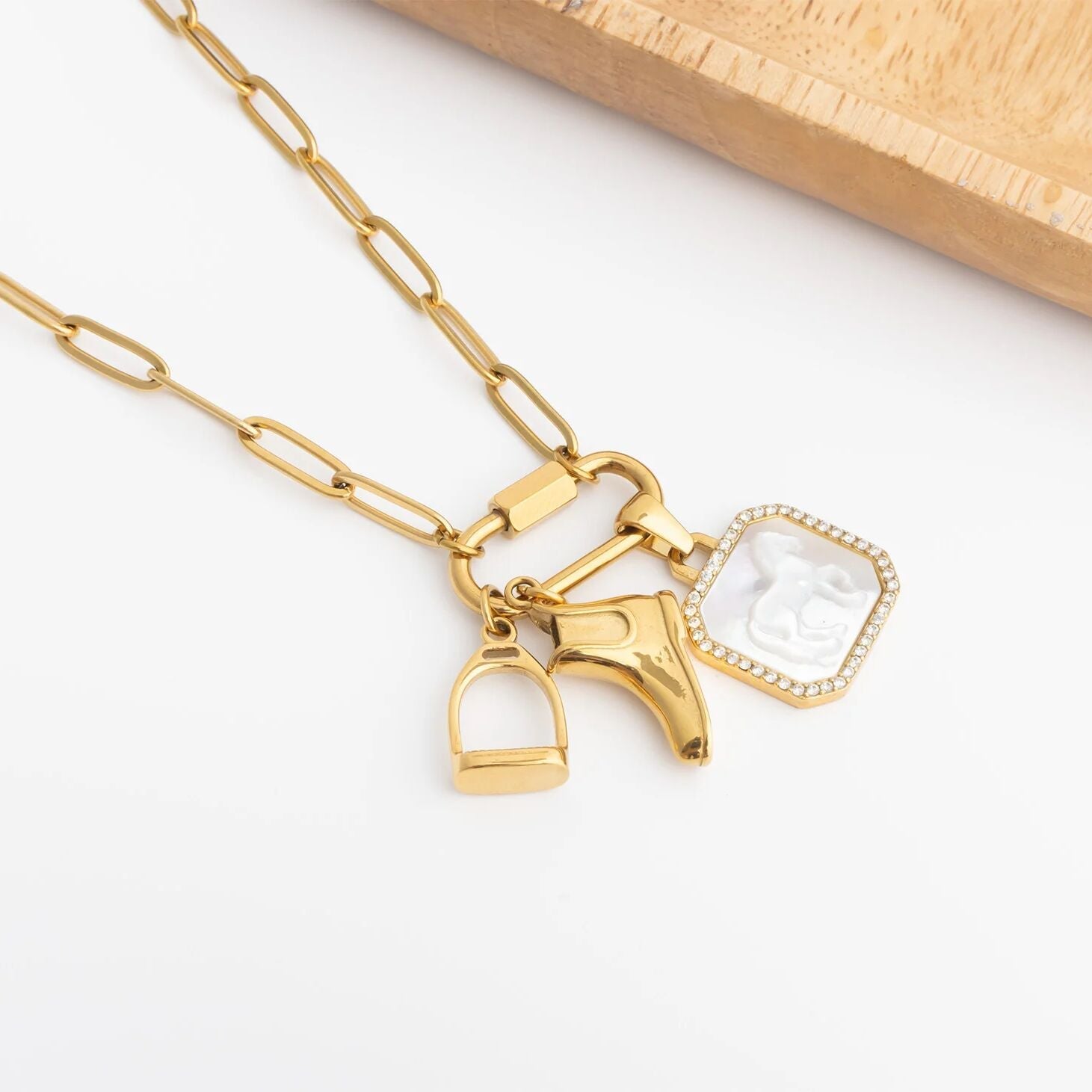 Gold necklace with horse, stirrup and boot charms on a white background