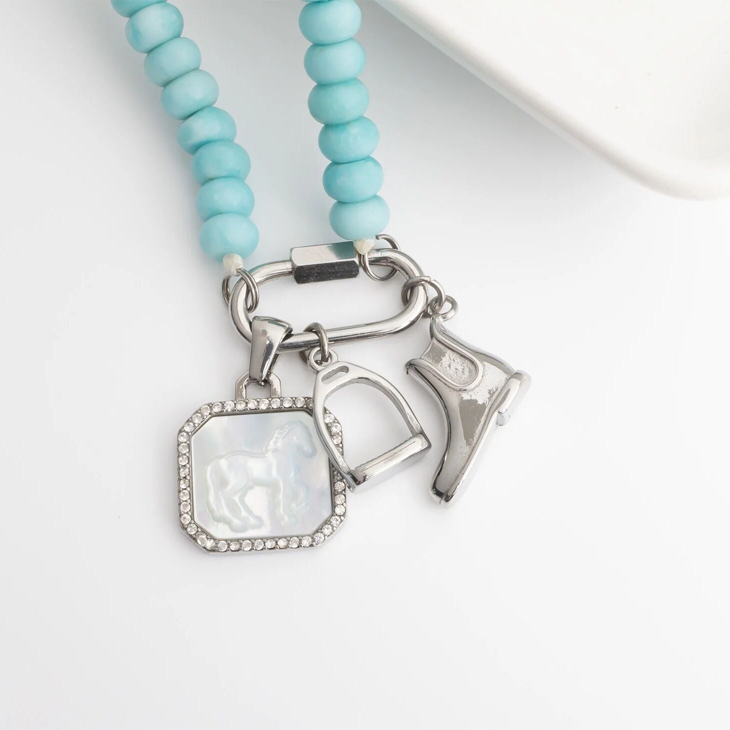 Necklace with turquoise beads and silver charms on a white background
