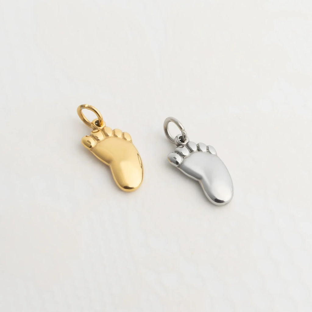 Gold and silver Baby Foot Charm on a light gray background