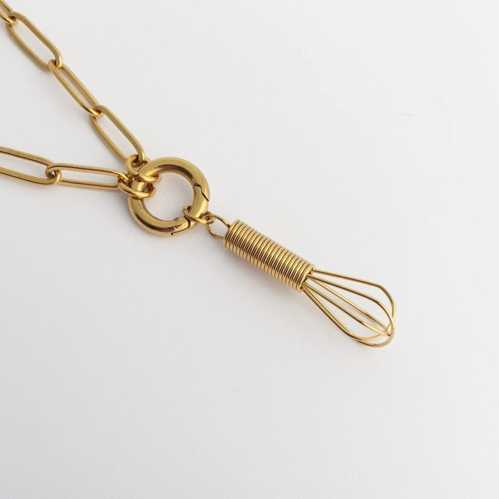 Gold necklace with a whisk-shaped pendant on a white background