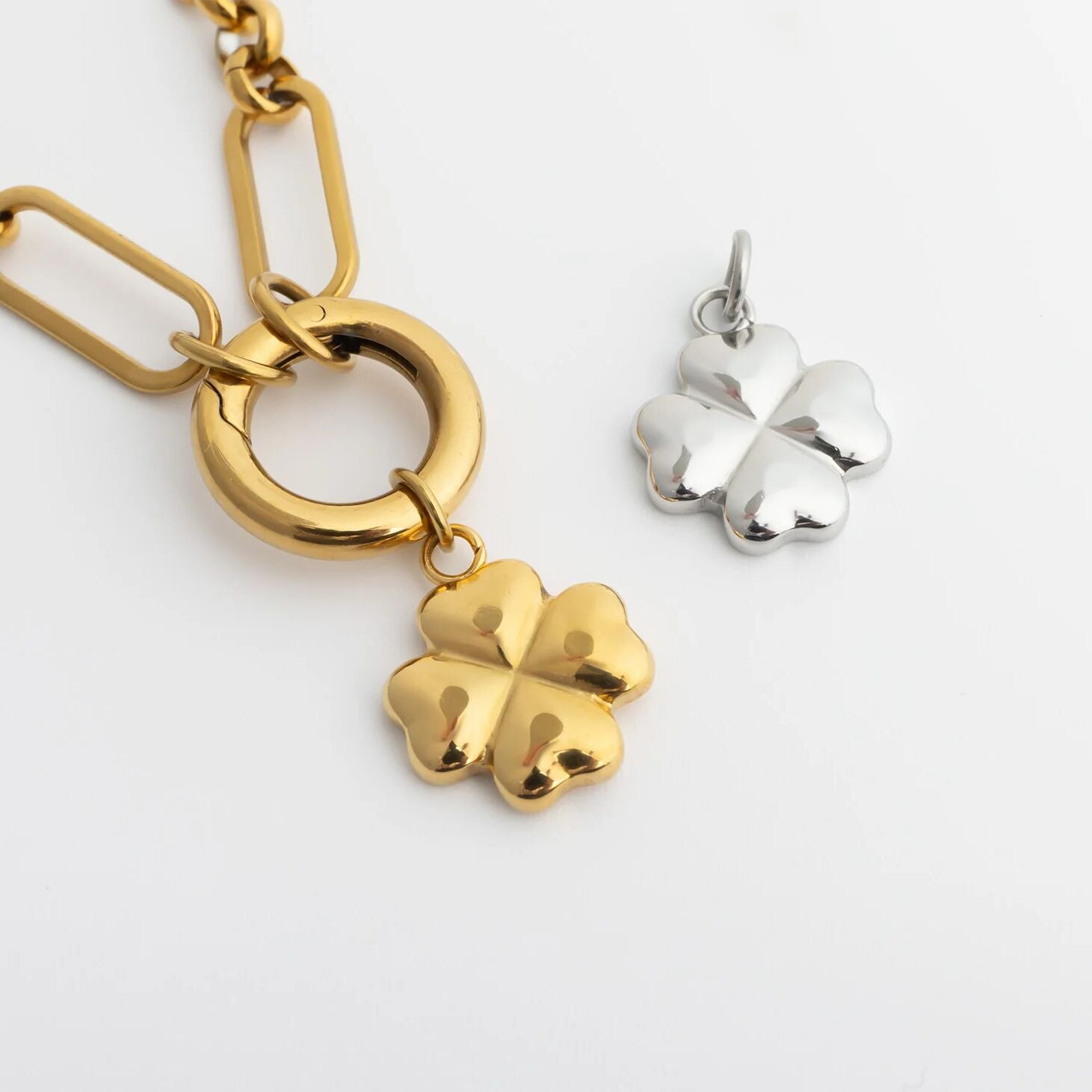 Gold and silver four-leaf clover charms on a white background