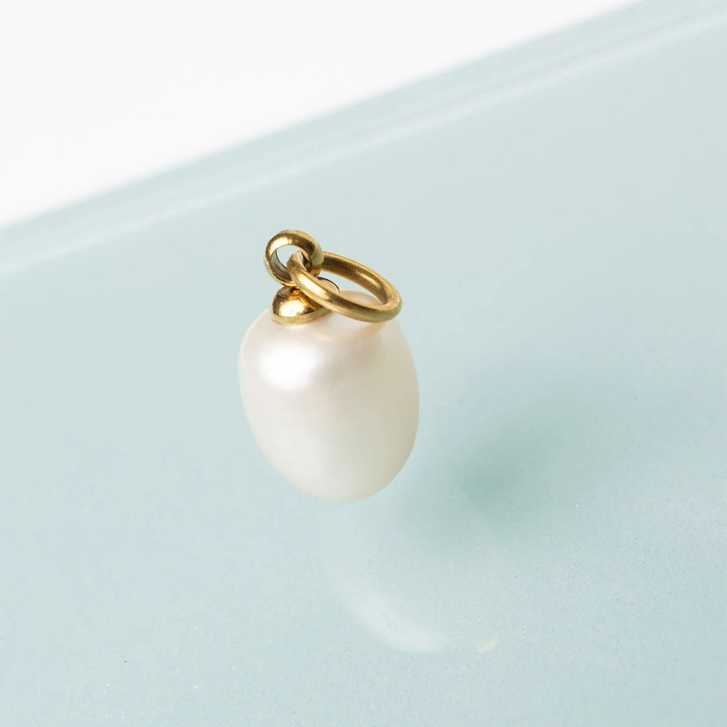 Pearl charm on a gold chain against a light blue background