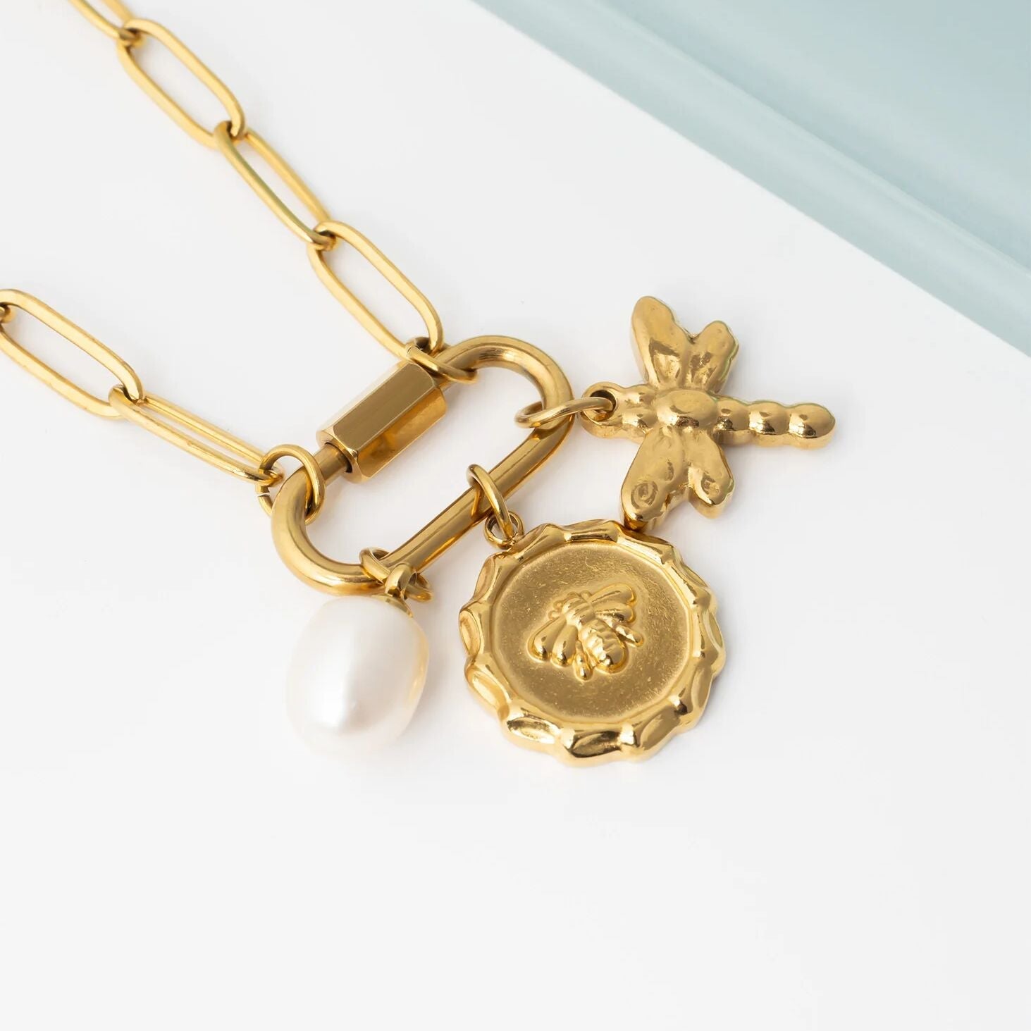 Gold necklace with a round pendant and chain on a light background