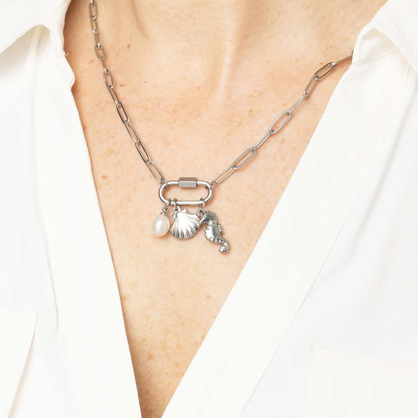 Necklace with charms on a person wearing a white shirt