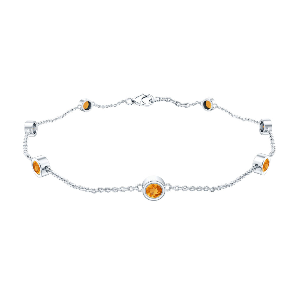 A silver bracelet with small orange gemstones attached to it.