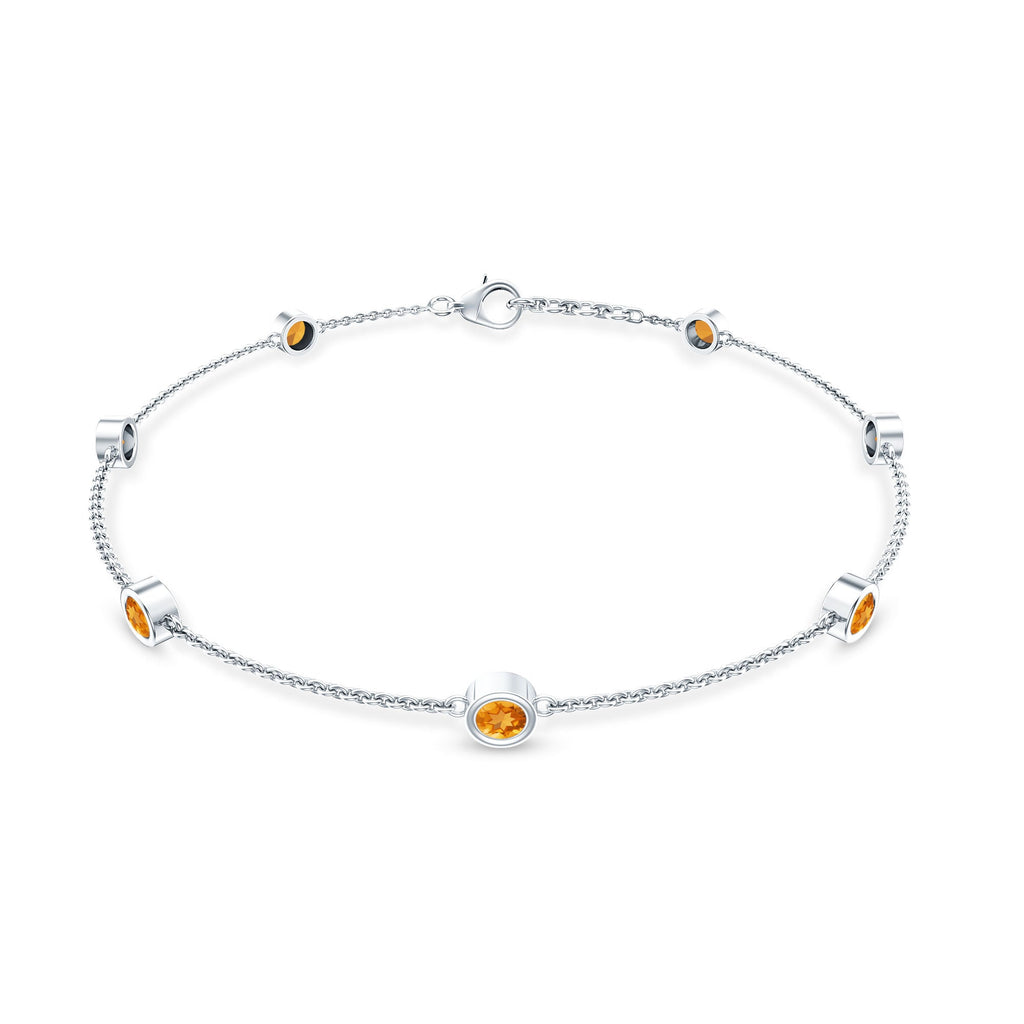 A silver bracelet with small orange gemstones on a white background.