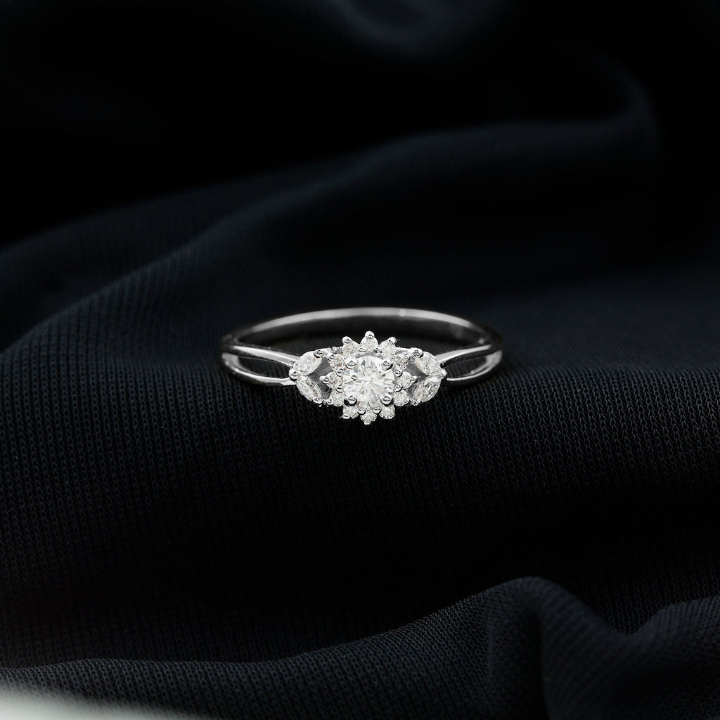 A diamond engagement ring with a large central diamond surrounded by smaller diamonds is displayed on a dark fabric background.