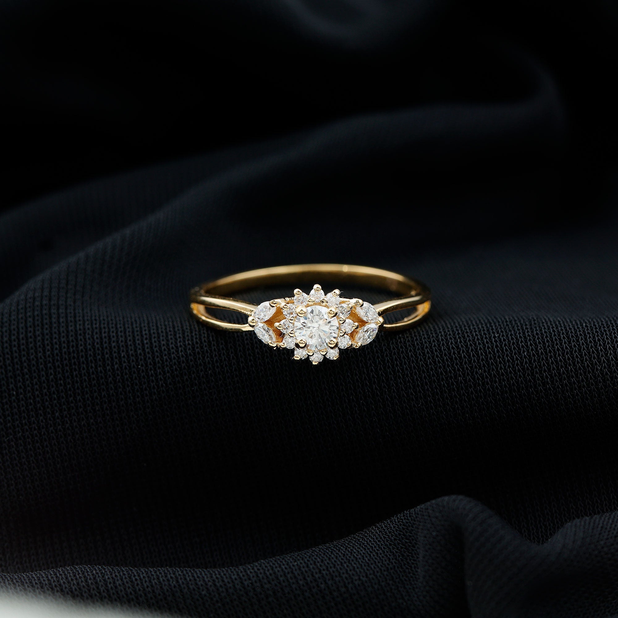 A gold ring with a large diamond center stone is displayed on a black fabric background.