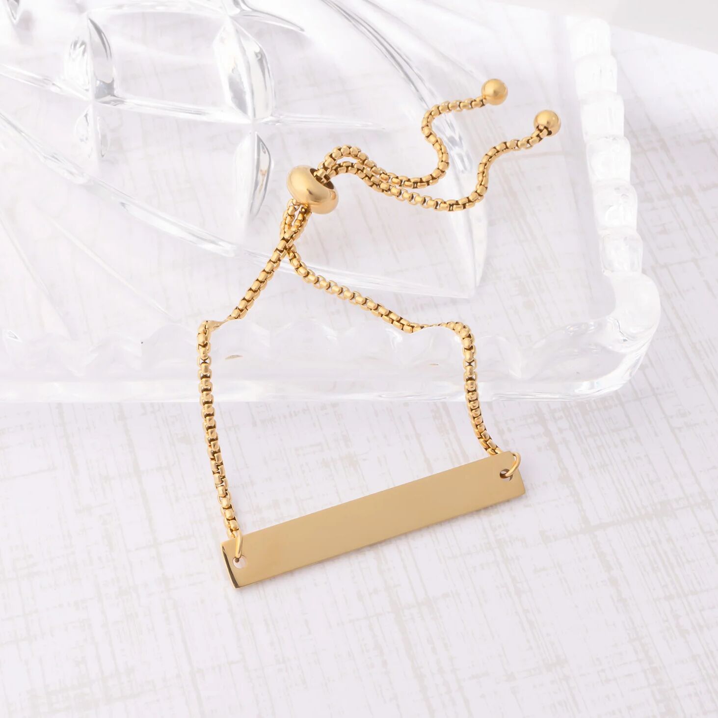 Gold necklace with a rectangular pendant on a white background