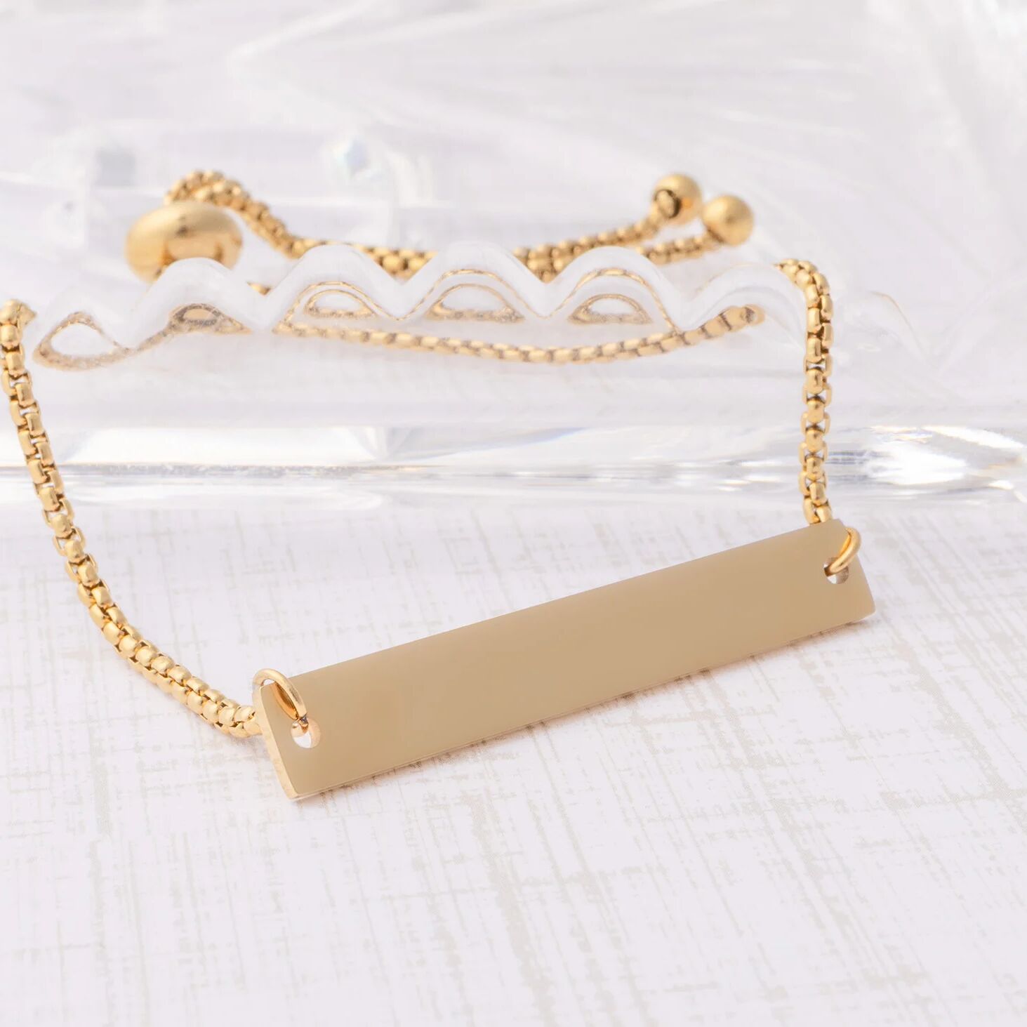 Gold bar necklace on a white lace background