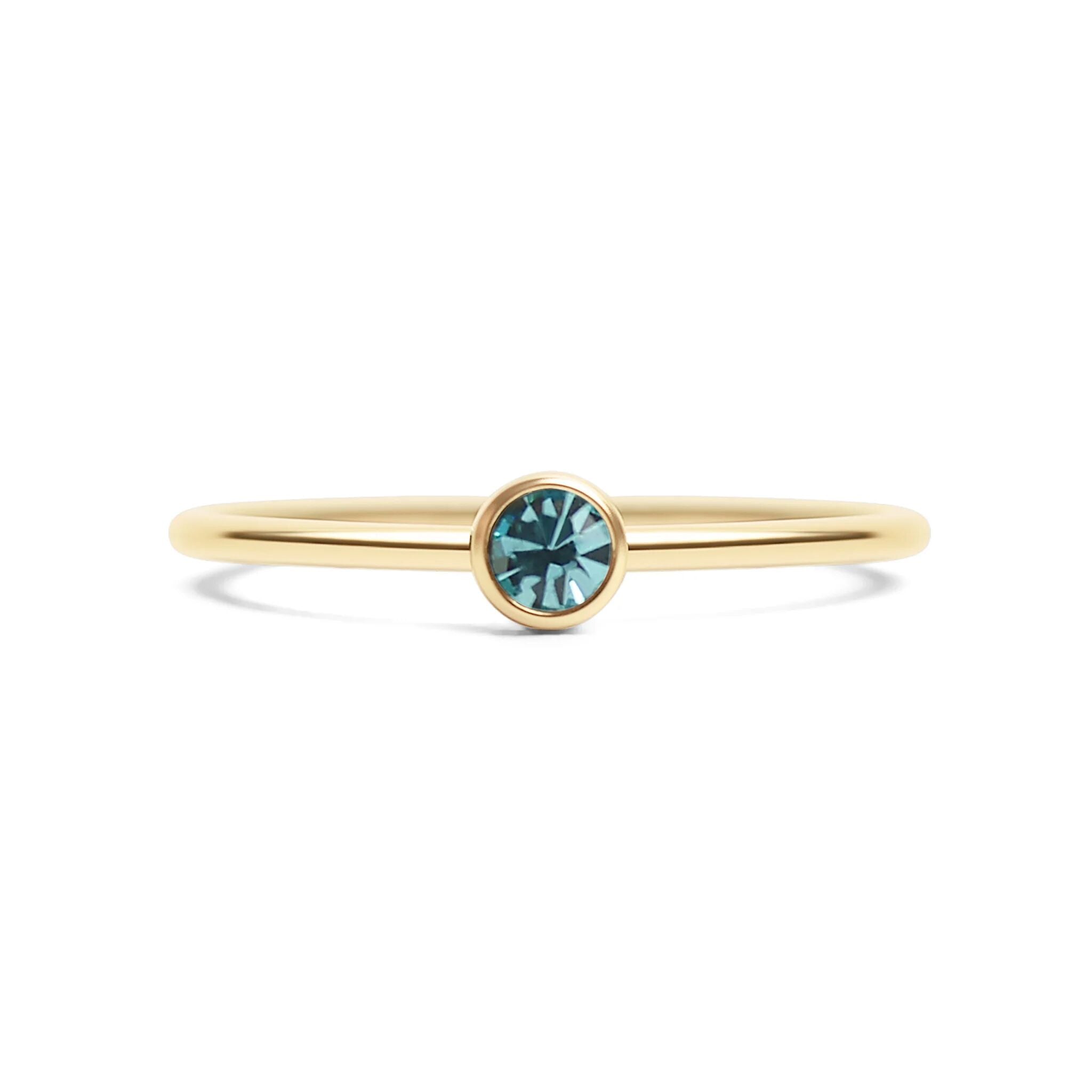 Gold ring with a blue gemstone on a white background