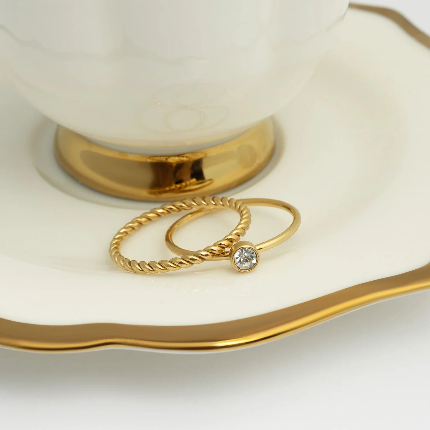 Gold rings with a diamond on a white dish with gold rim