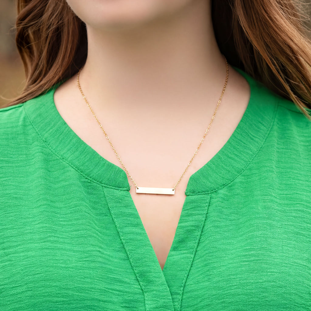 Gold necklace on a person wearing a green top