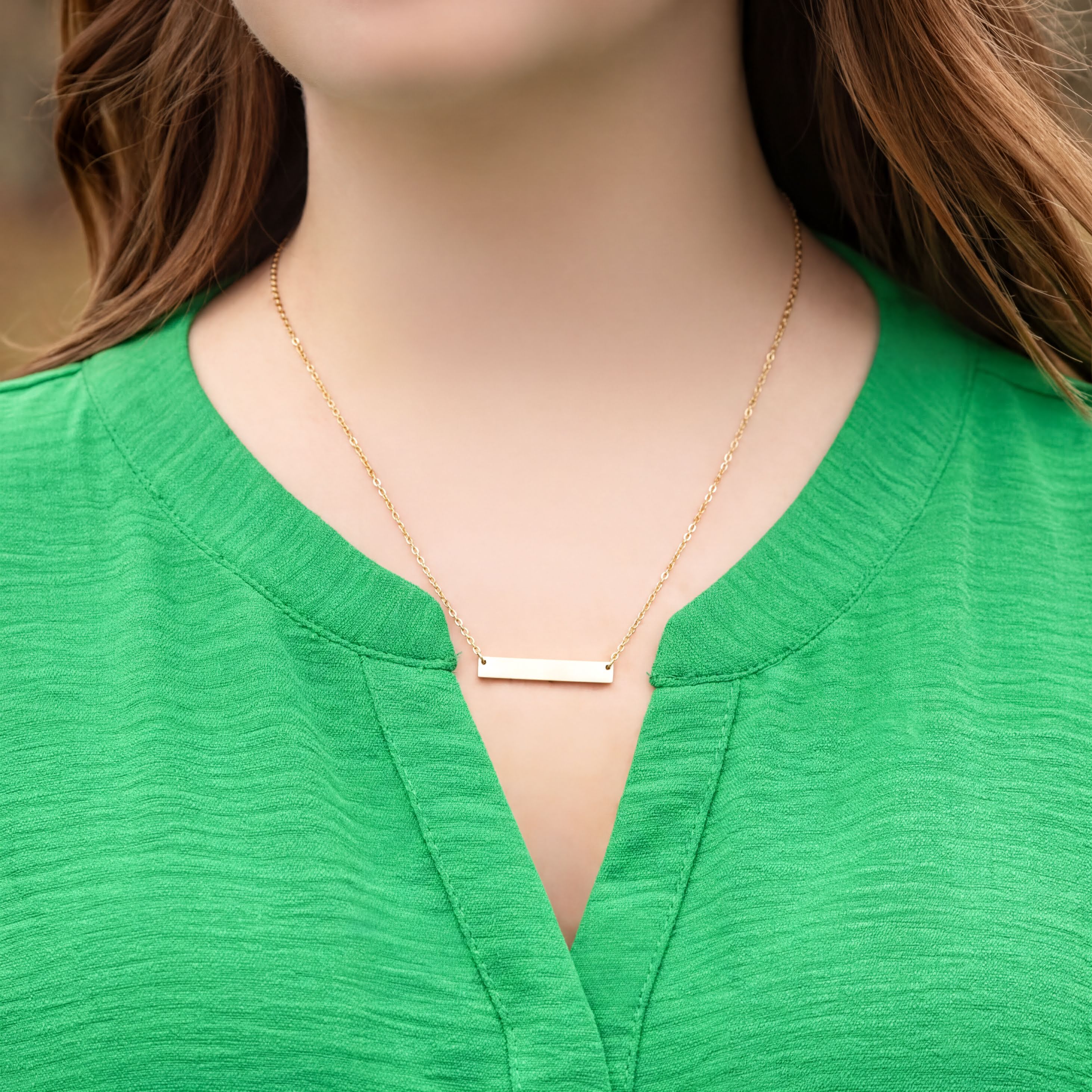 Gold necklace on a person wearing a green top