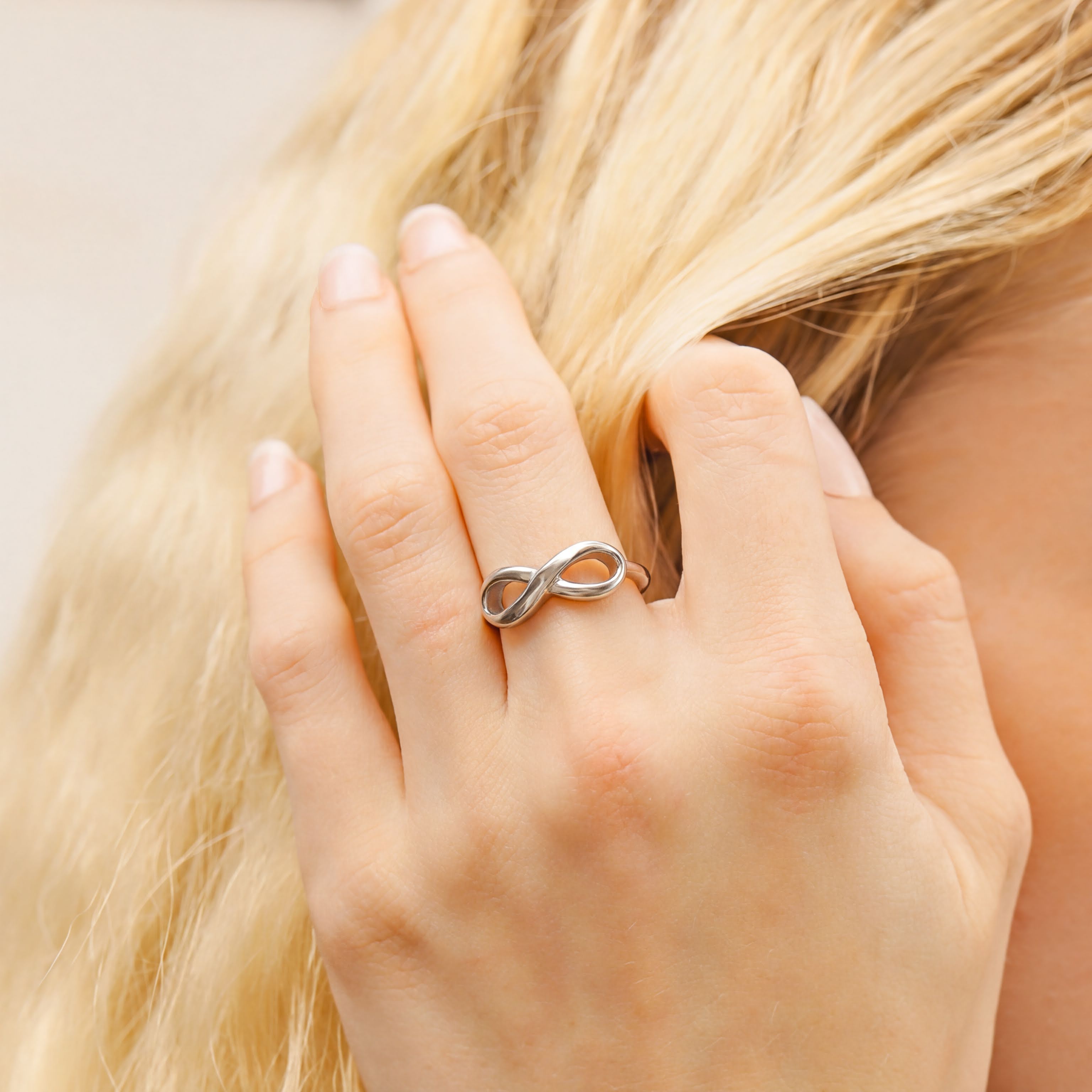 A close-up of a person's hand wearing a silver ring with an infinity symbol on it.