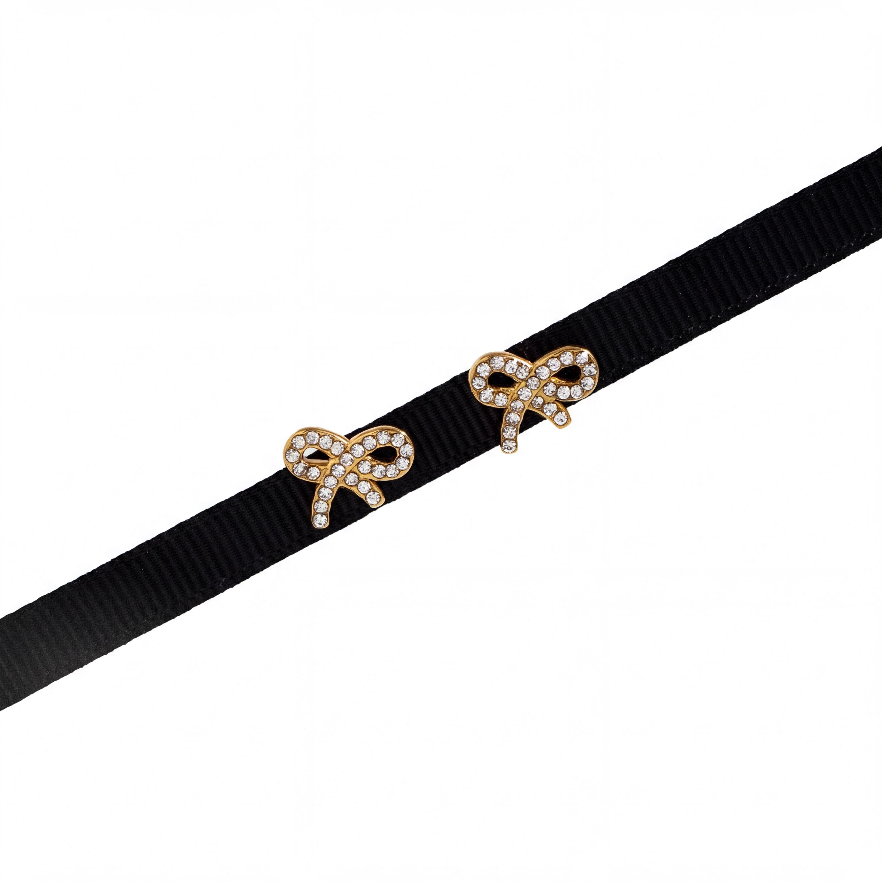 two gold-colored earrings with small diamonds on a black ribbon.