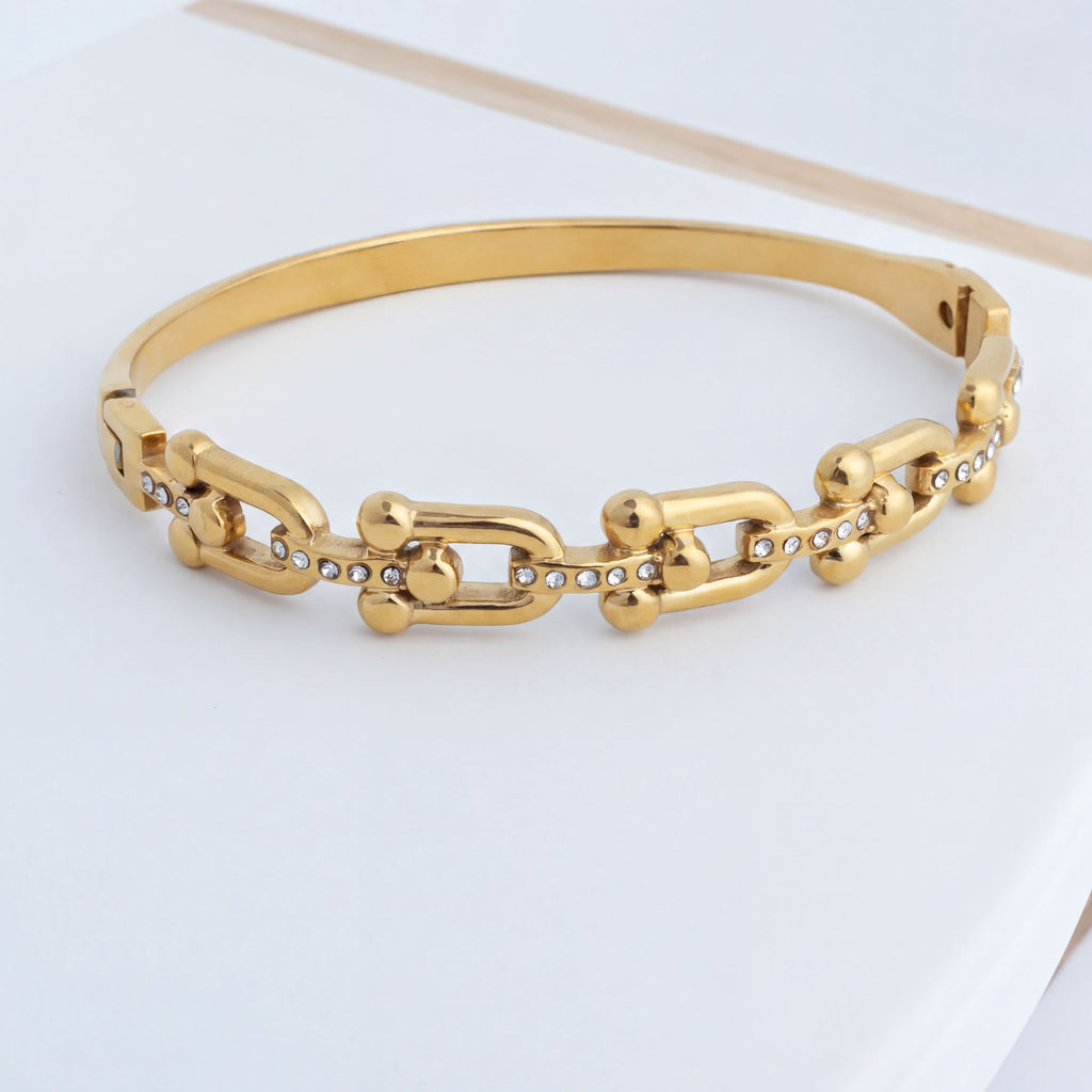 Gold chain bracelet on a light gray background