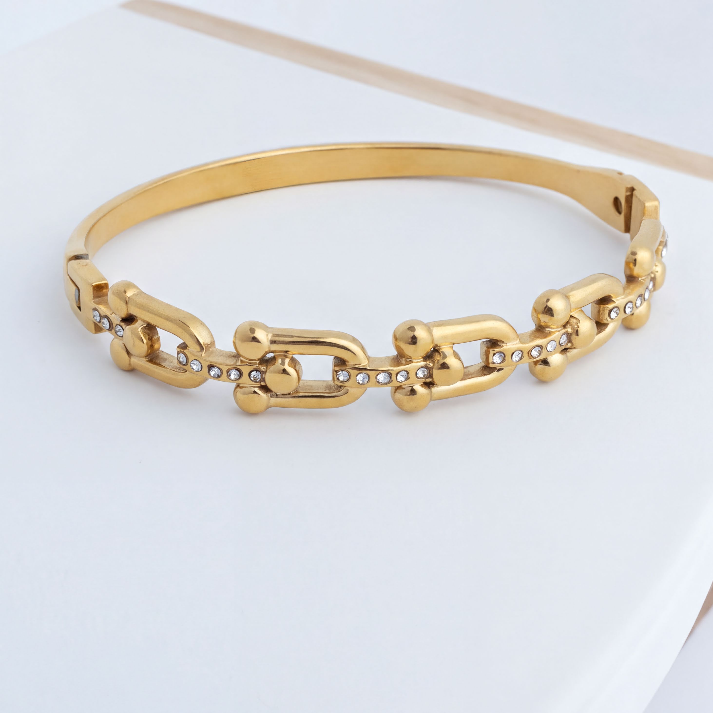 Gold chain bracelet on a light gray background