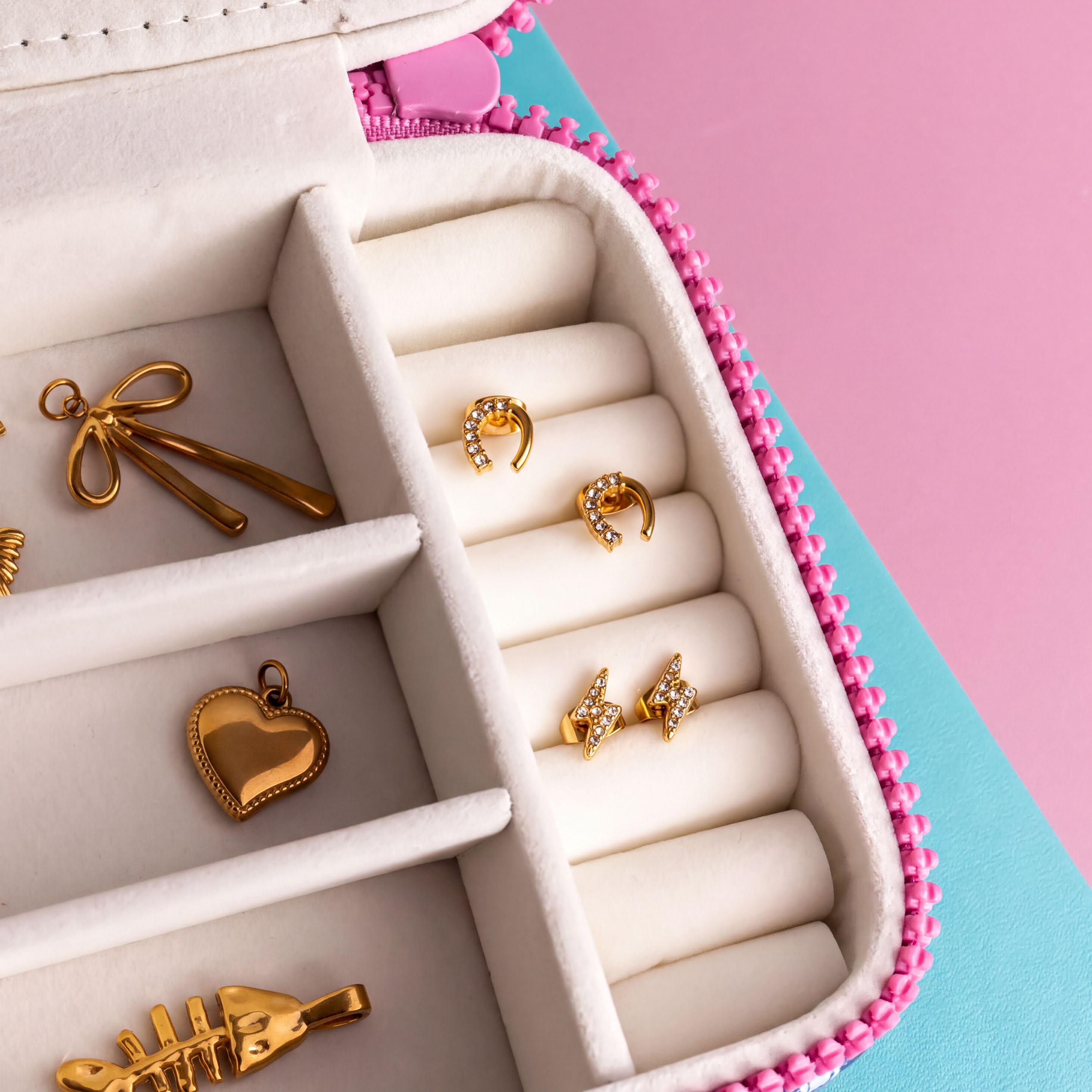 A jewelry box containing various pieces of jewelry, including earrings, a heart-shaped charm, and a small pendant.