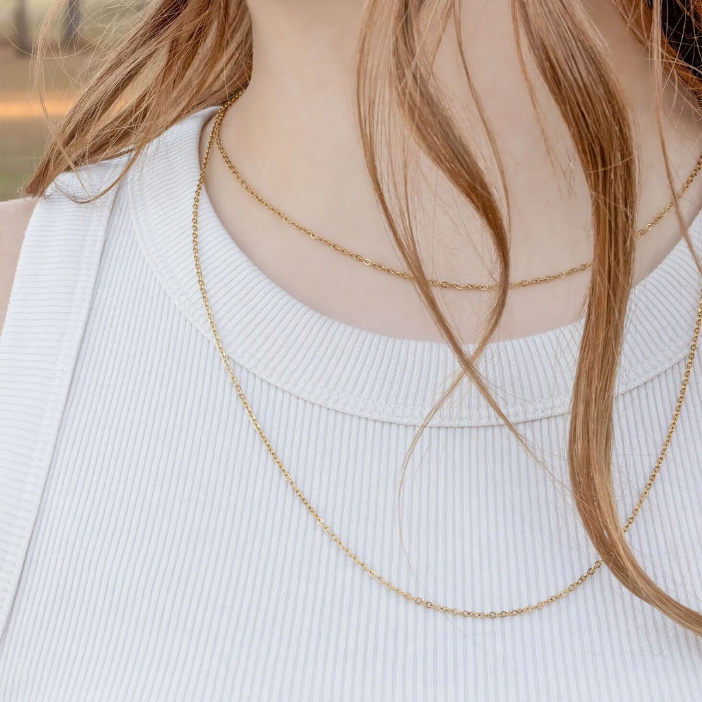 Close-up of a person wearing a delicate gold necklace with a blurred background