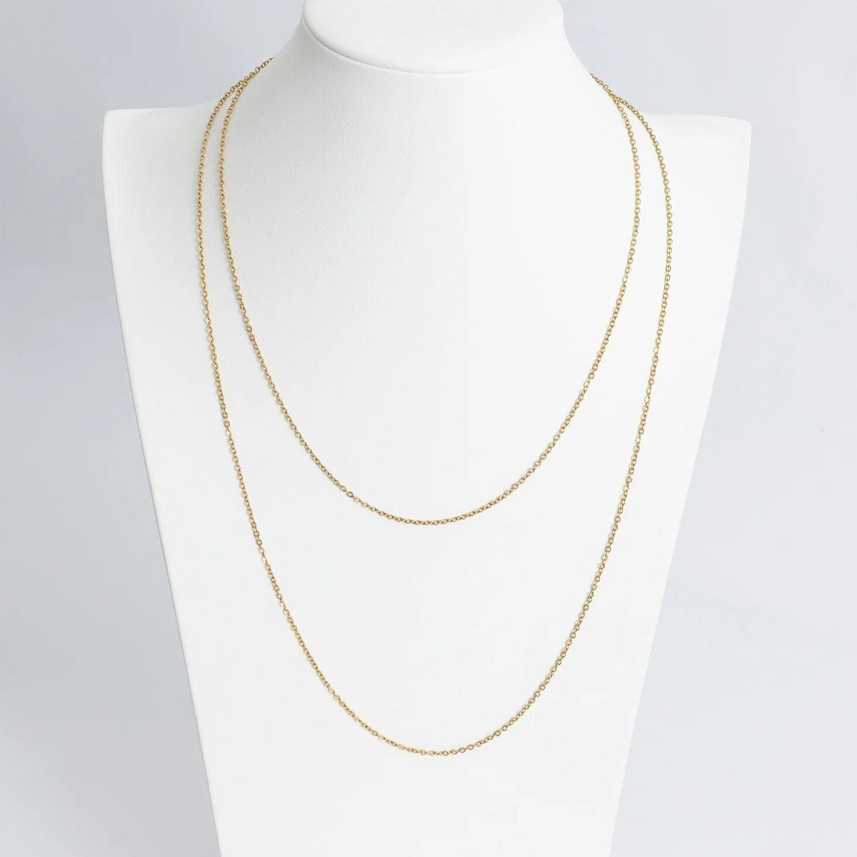Gold chain necklace on a mannequin with a plain background